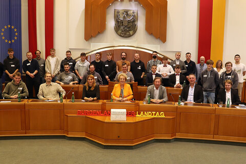 Landtagspräsidentin Verena Dunst (Mitte vorne) mit den Landtagsabgeordneten Wolfgang Spitzmüller (2.v.l., sitzend, GRÜNE), Dipl-Päd. DI Carina Laschober (3.v.l., sitzend, ÖVP), Mag. Kurt Maczek (3.v.r., sitzend, SPÖ) und MMag. Alexander Petschnig (sitzend, 2.v.r.) sowie Auslandsdiener Jonathan Dorner (sitzend, vorne, r.) mit den Schülern sowie ihren Lehrern Tanja Illedits, BEd und Ing. Georg Krammer, BEd von der Berufsschule Oberwart im Landtagssitzungssaal.
