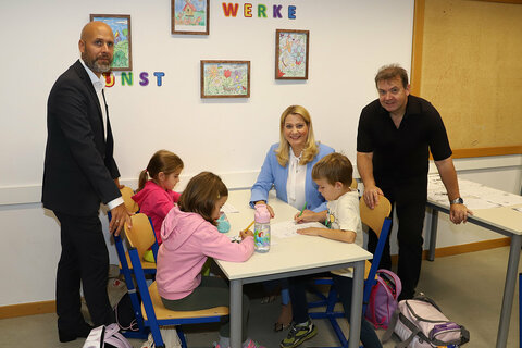 Hannes Schmid, Schulleiter der BHAK und BHAS Frauenkirchen und Bürgermeister der Stadtgemeinde Frauenkirchen, Bildungslandesrätin Mag.a (FH) Daniela Winkler und Clusterleiter Norbert Kappel (v.l.n.r.) mit Kindern beim Ausfüllen von Arbeitsblättern.